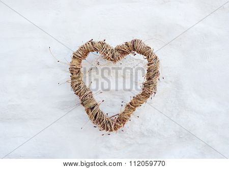Rustic heart shape made from twig branches hanging on farmhouse country whitewash brick wall, background for wedding invitation or card