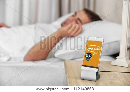 Beautiful young man waking up with mobile alarm clock
