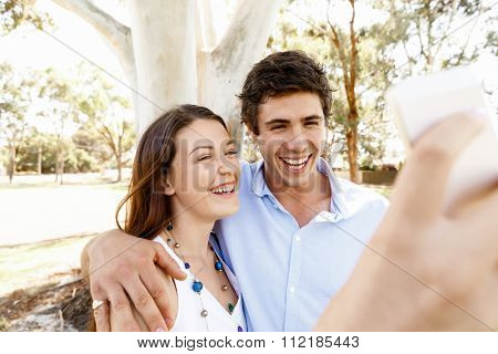 Young couple in the park making their selfi with mobile phone