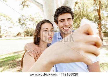 Young couple in the park making their selfi with mobile phone