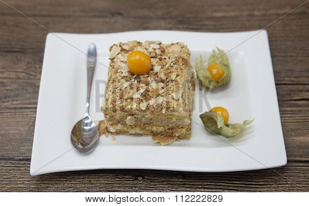 Fresh delicious diet cake with berry Physalis at Dukan Diet on a porcelain plate with a spoon on a wooden background