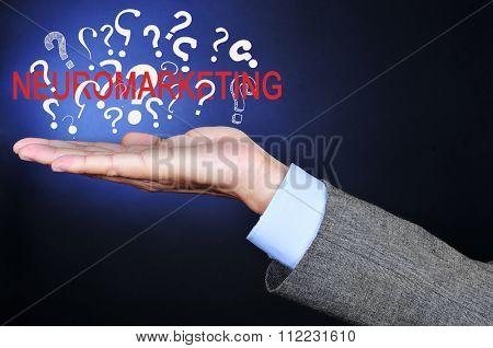 closeup of a young caucasian businessman with the word neuromarketing and a pile of question marks in his hand