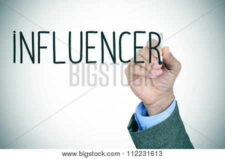 closeup of the hand of a young caucasian man in suit writing the word influencer with a pen in the foreground