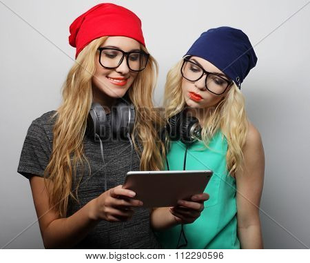 two hipster girls friends use digital tablet, studio shot over gray vackground