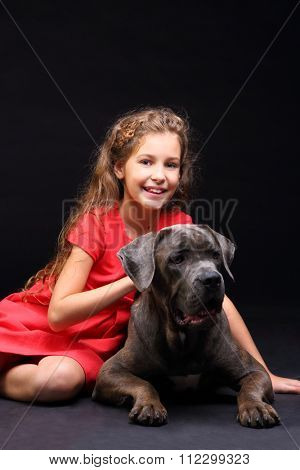 Happy beautiful girl in red dress with a big dog isolated on black