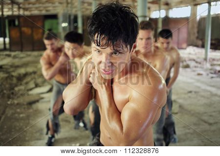 five healthy young guys with force pulling ropes load in abandoned building 