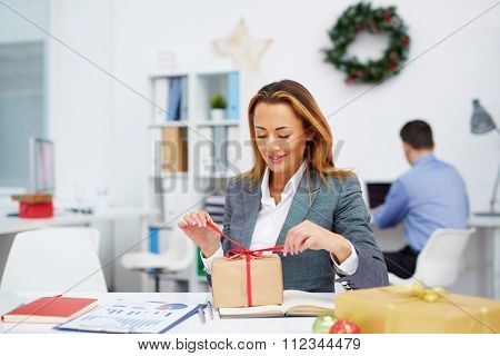 Young businesswoman unpacking gift-box in office