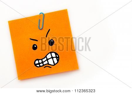 Angry face against orange adhesive note with a paperclip