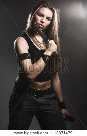 Sexy woman holding daggers with smoke. studio shot
