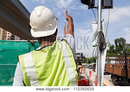 Surveyor Gesturing After Taking Readings Of Dumpy Automatic Level Instrument