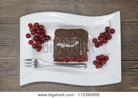 Red Velvet, fresh delicious diet cake with red currant at Dukan Diet on a porcelain plate with a spoon on a wooden background.