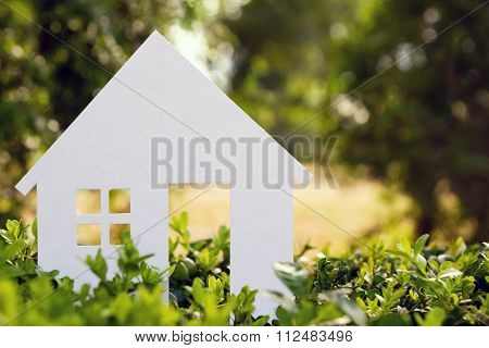 Hand holding white paper house against green background. Real Estate Concept