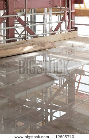 A Construction Site With Concrete Slab With Water Puddle And Scaffolding
