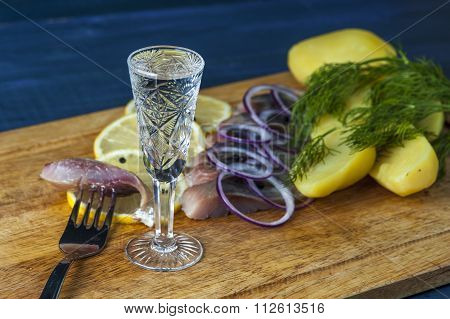 Glass of vodka, herring, red onion and potatoes