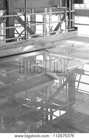 A Construction Site With Concrete Slab With Water Puddle And Scaffolding