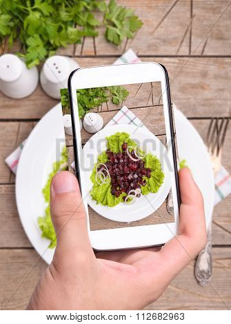 Hands taking photo beet salad with smartphone
