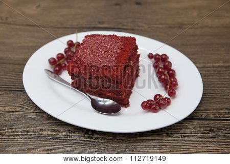 Red Velvet, fresh delicious diet cake with red currant at Dukan Diet on a porcelain plate with a spoon on a wooden background.