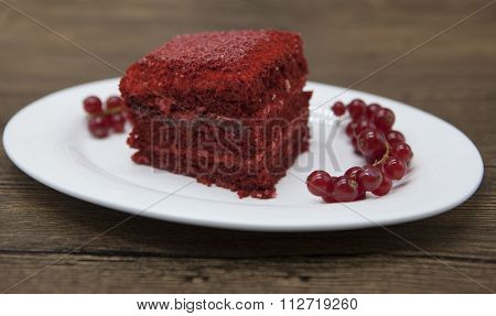 Red Velvet, fresh delicious diet cake with red currant at Dukan Diet on a porcelain plate with a spoon on a wooden background.