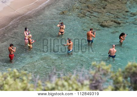Tourists Enjoy The Clear Water Of The Beautiful Beach In Tsigrado Beach In Milos Island, Cyclades, G