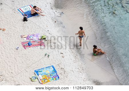 Tourists Sunbathing At The Beautiful Beach In Tsigrado Beach In Milos Island, Cyclades, Greece
