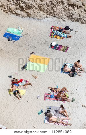 Tourists Sunbathing At The Beautiful Beach In Tsigrado Beach In Milos Island, Cyclades, Greece