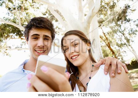 Young couple in the park making their selfi with mobile phone