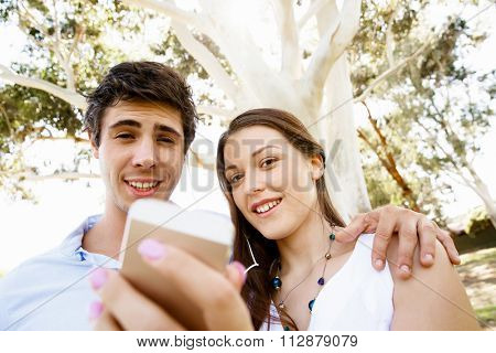 Young couple in the park making their selfi with mobile phone