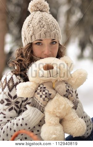 Beautiful, nice, smiling, little, attractive, wearing sweater, hut, mittens, girl with a fluffy, soft, beige, hite, teddy bear, cute toy, curly, light hair in snow, winter, frosty forest, sweet bear, tiny bear, petite