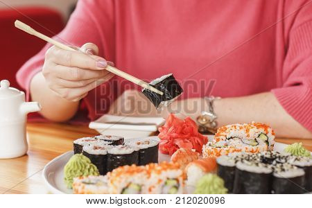 The Best Sushi Rolls, Japanese Cuisine. Various Delicious Sushi Rolls. The Hand Is Dipped In Soy Sau