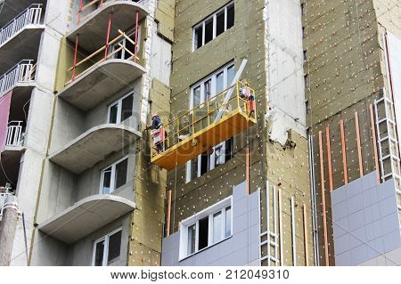 work with yellow front suspended cradle on a newly built high-rise building.