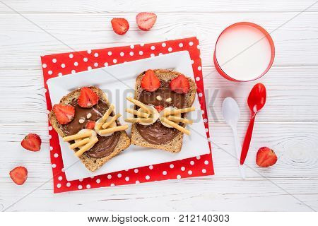 Sandwiches and milk for children's breakfast. Funny cats face sandwiches with berry chocolate banana nuts. Top view
