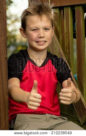 Pre-teen boy giving ok gesture sitting outside