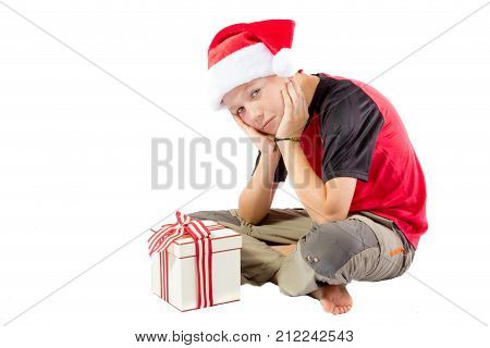 Sulky pre-teen boy with a christmas gift isolated on white background