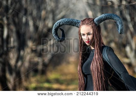 beautiful woman dressed as a fairy witch in raincoat and with horns