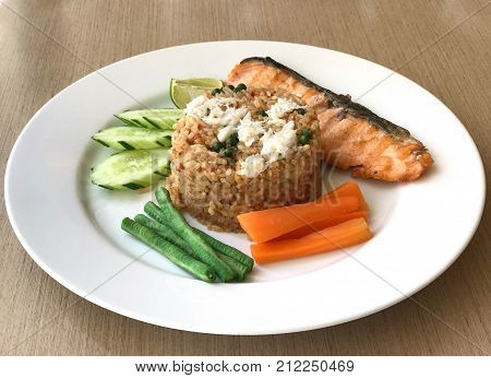 Fried rice with chili paste topped with crab and served with grilled salmon Thai food