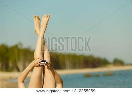 Summertime pleasures enjoying vacation concept. Woman in bikini sunbathing and relaxing on beach using smartphone checking social media and writing sms