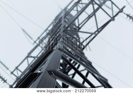 Atmospheric photo of the high voltage transmission tower standing on the gray sky background after blizzard