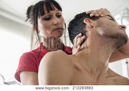 physiotherapist massages young patient to cure a cervical pain