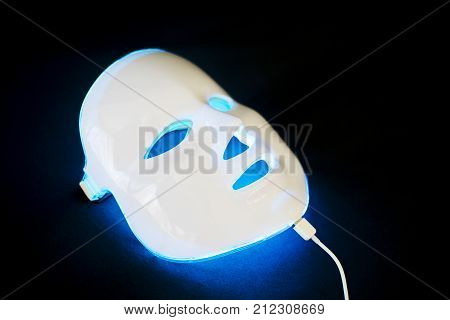 Light rejuvenating mask for facial skin therapy on black background