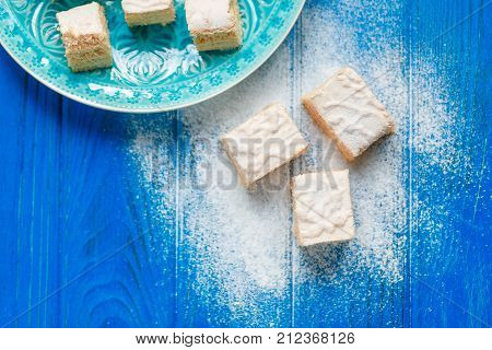 Biscuit cake pie apple candy pastila on blue wood cutting board background. Small square pieces paste. Top view photo