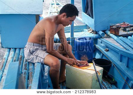 Puerto Princesa Philippines - May 9 2009: Fisherman fillets the freshly caught tuna before serving it raw to tourists on a whale shark tour near the coast of Palawan Island The Philippines