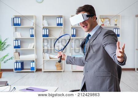 Businessman playing virtual reality tennis in office with VR gog