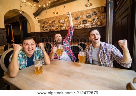 Group Of Young Beautiful Friends Watching Tv And Cheering For Their Team While Resting In Pub.