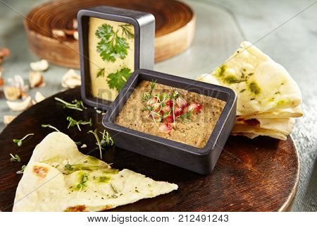 Menu of gastronomic restaurant. Cold appetizer - hummus of chick pea and eggplant pate with fresh herbs and pomegranate seeds on wooden round board