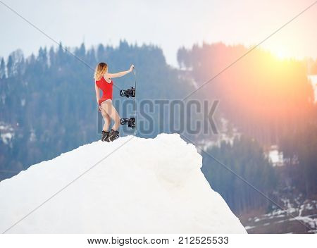 Hot Woman Snowboarder Wearing Red Swimsuit, Standing With Snowboard On Snowy Slope At Ski Resort, En