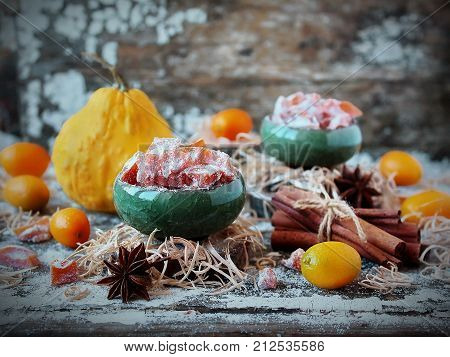 homemade candied pumpkin and orange in powdered sugar on old wooden background