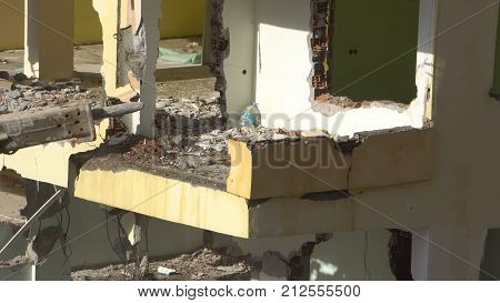the process of destruction of the old building with heavy machinery.