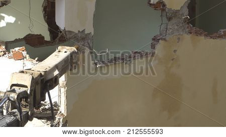 the process of destruction of the old building with heavy machinery.
