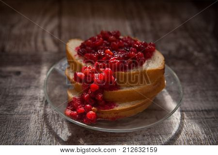 Lingonberry jam on a slice of bread in the sunlight. Glowing berry's cow berry jam.