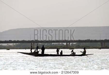 BAMAKO, MALI - CIRCA FEBRUARY 2012: Silhouette of Bozo fishermen and children on a pirogue on the river Niger in Bamako.